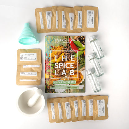 The Spice Lab contents with spice packets, a mortar and pestle, and a funnel on a white background.
