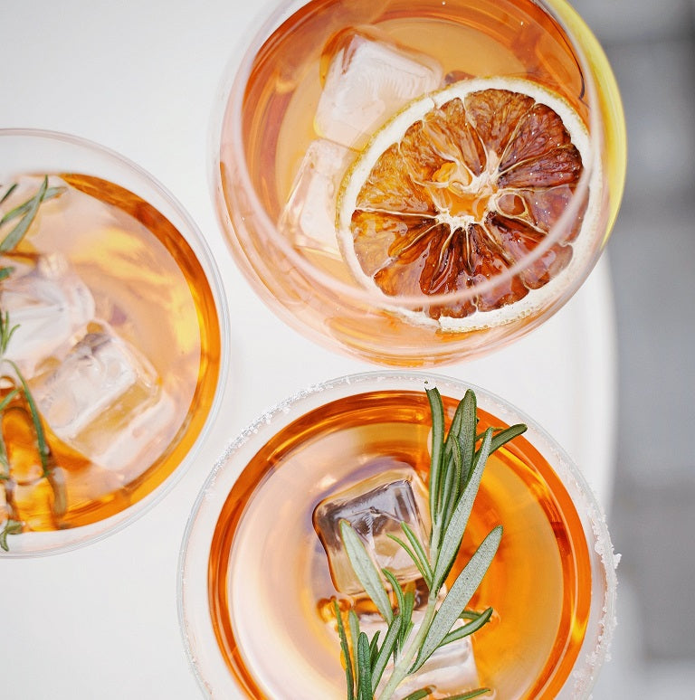 top down view of some fresh lemonades and cocktails with ice cubes and rosemary and blood oranges as garnishes