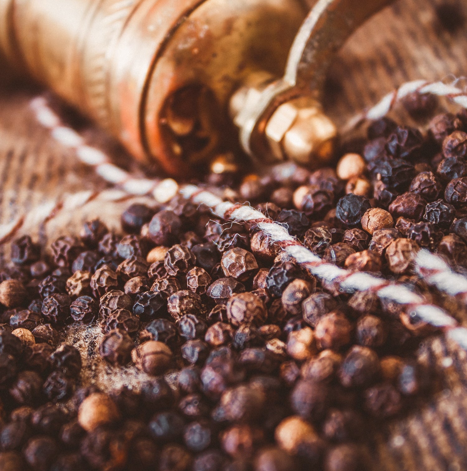 peppercorns spread out on a table with a grinder in the background